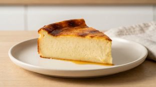 Une part de flan parisien à la vanille posée sur une assiette claire sur une table en bois.